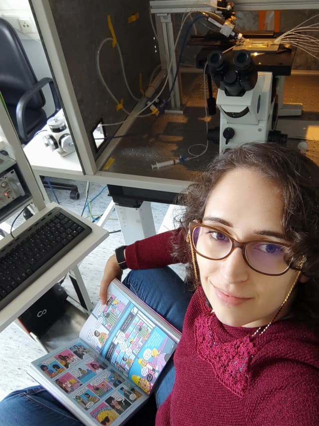 Profile picture of Sandrina reading while waiting for results from the electrophysiology setup at the lab